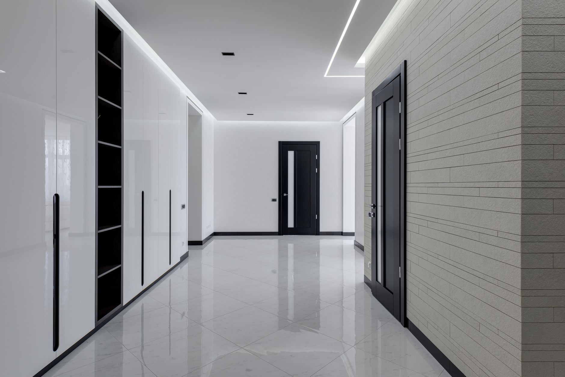 Wide corridor in modern house with white tiled walls and floor black wooden doors and shelves for storage in Riverside, CA